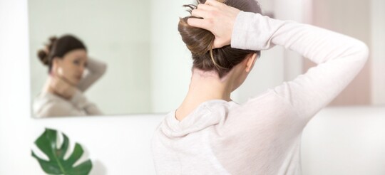 Frau mit Psoriasis betrachtet sich im Spiegel