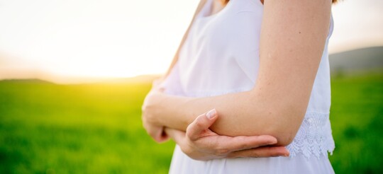 Frau im Sommerkleid ohne Schuppenflechte am Arm