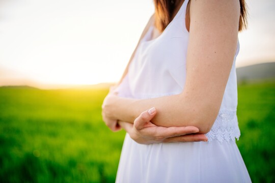 Frau im Sommerkleid ohne Schuppenflechte am Arm