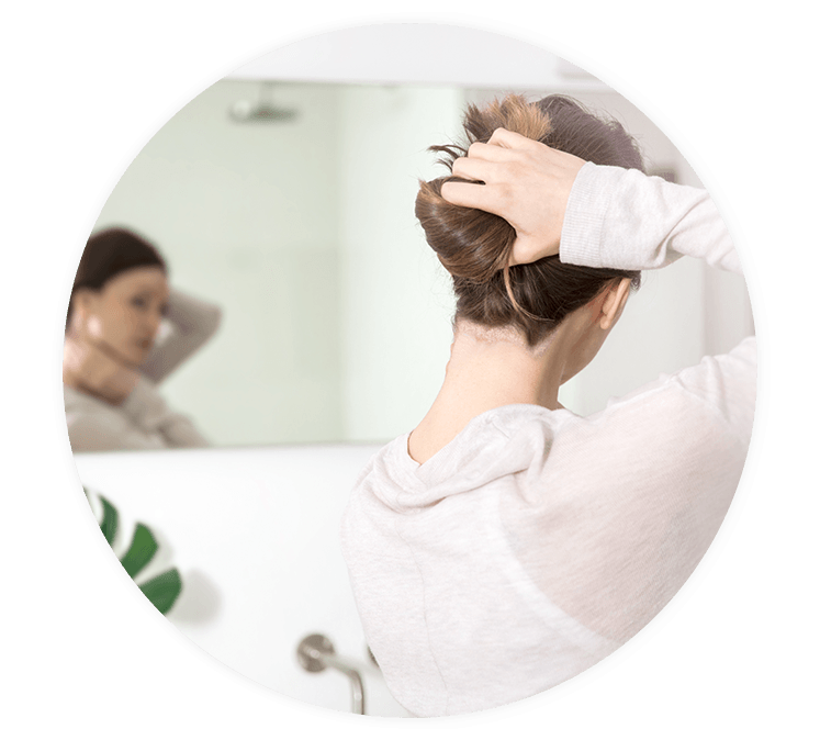 Frau mit Psoriasis betrachtet sich im Spiegel